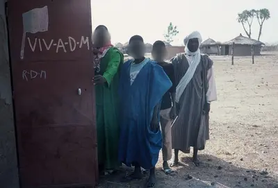 Des habitants devant un mur sur lequel est écrit « Vive l'ADM »