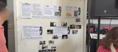 Un panneau blanc couvert de textes et de petites photos, avec le mot Unesco en bas.