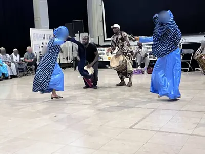 Deux danseuses en robes bleues évoluant sur la piste autour d'un joueur de djembé.