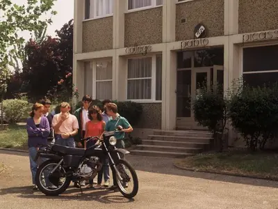 Des collégiens français devant un bâtiment, avec la moto collectée pour Melga.